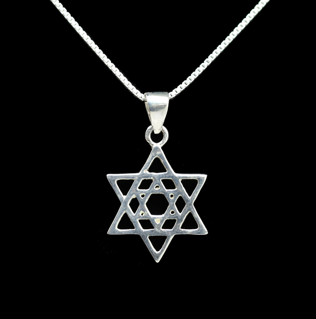 A sterling silver Star of David pendant necklace on a delicate silver chain, set against a solid black background.