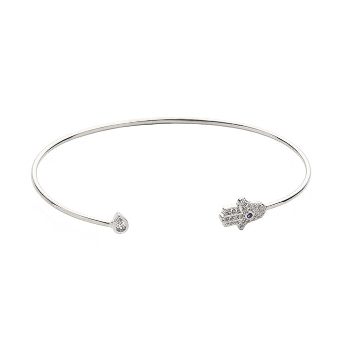 A silver-toned open cuff bangle bracelet featuring a small Hamsa hand charm on one end and a tiny round clear stone on the other, set against a plain white background.