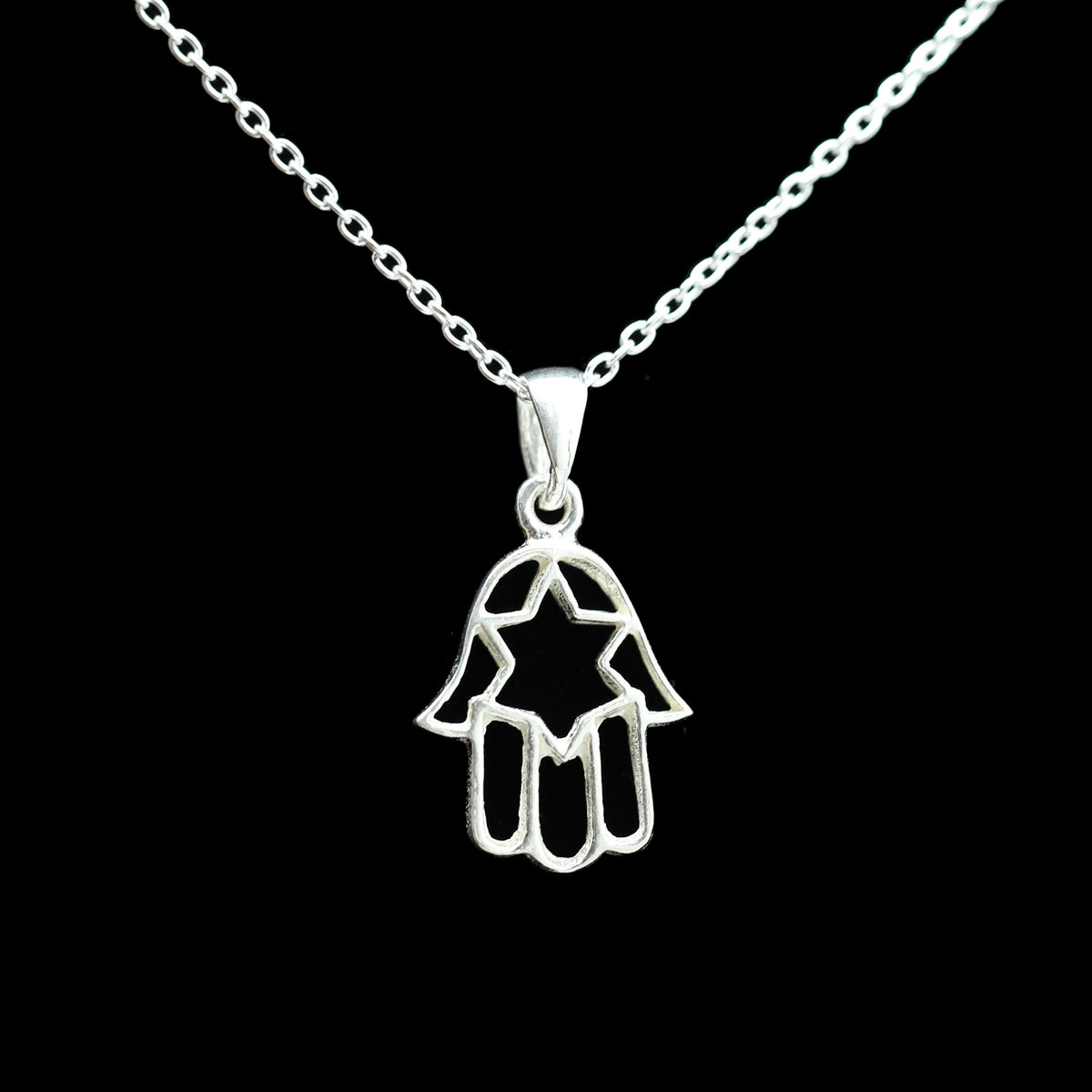 A sterling silver Hamsa hand pendant necklace with a star cutout, suspended from a delicate link chain against a solid black background.